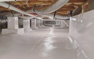 Spacious crawl space with bright white vapor barriers on floor and walls. Insulated ducts run along the ceiling, creating a clean, well-lit environment.