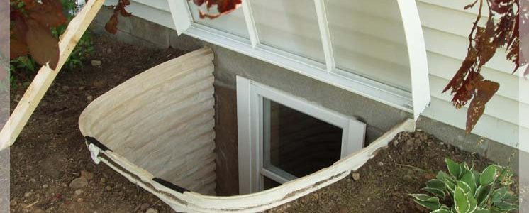 Basement egress window installation services showing a newly installed egress window well with protective cover for improved safety and waterproofing.